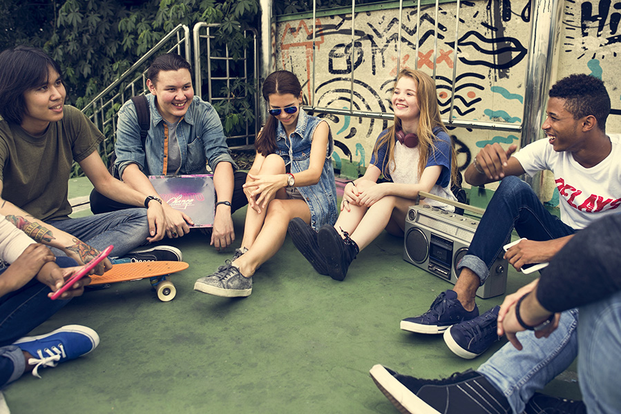 teenagers sitting together listening to music and laughing