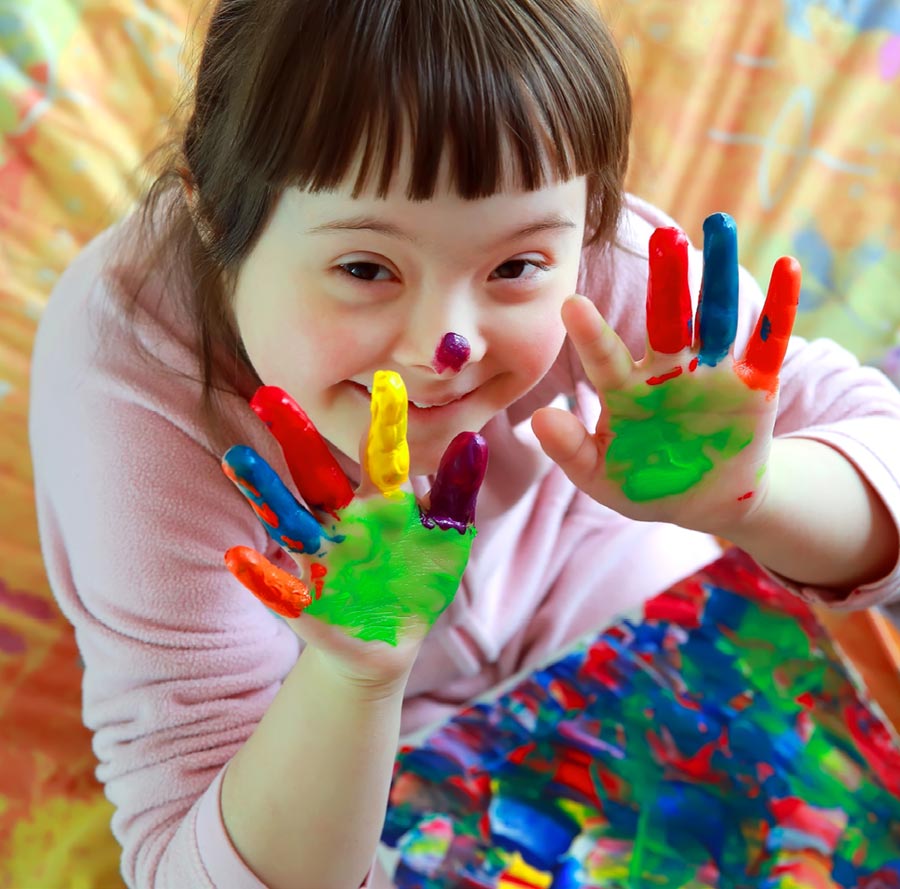 Special needs girl smiling and painting with hands