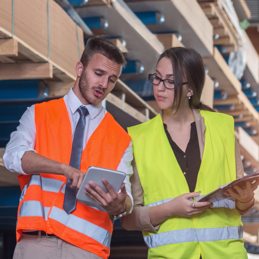 Male and female workers in hi-vis discussing while using tablet computers