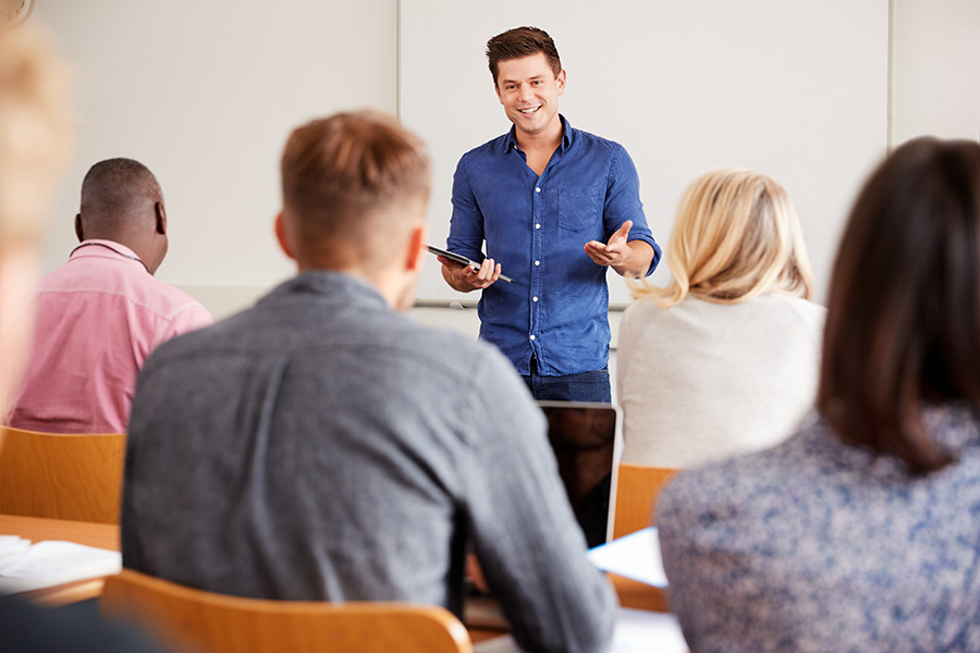 adult learners in class with smiling teacher